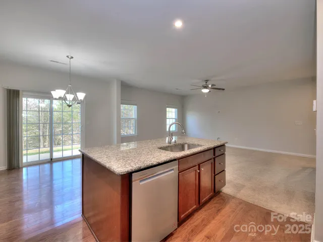 a kitchen with a granite countertop kitchen island a sink stainless steel appliances and living room view