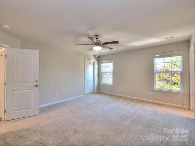 an empty room with windows and ceiling fan
