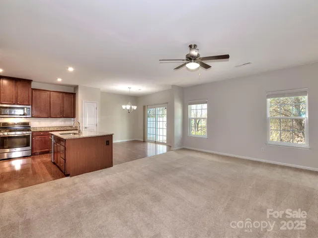 a large kitchen with kitchen island granite countertop a stove a sink a refrigerator dining table and chairs