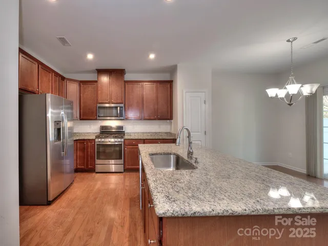 a kitchen with stainless steel appliances granite countertop a sink refrigerator and microwave