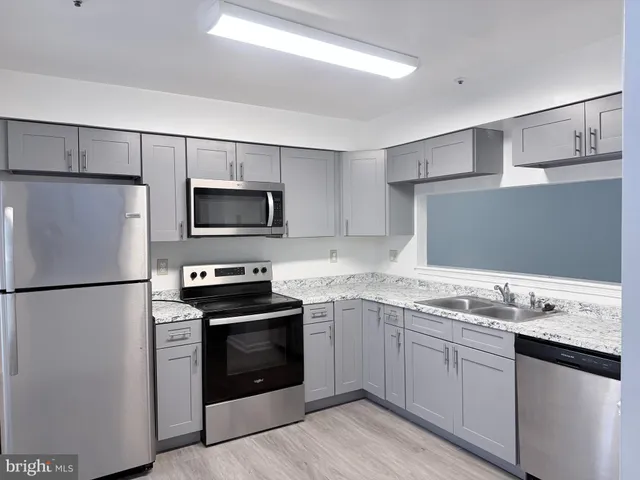 a kitchen with stainless steel appliances granite countertop a refrigerator stove a sink and white cabinets