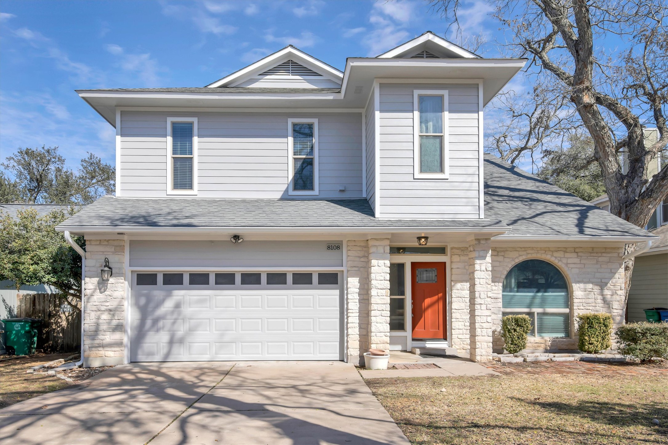 View of front of home with an attached garage, driveway, roof with shingles, and stone siding