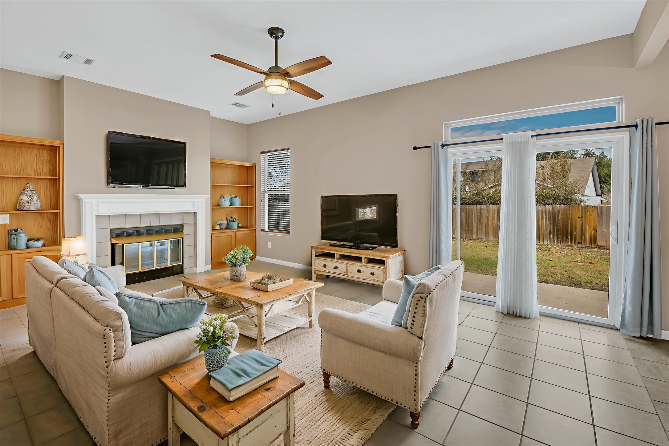 8108 Matchlock Cove Austin, TX 78729 - Photo 13 of 40 Living room featuring built in features, a ceiling fan, tile patterned flooring, and a tiled fireplace