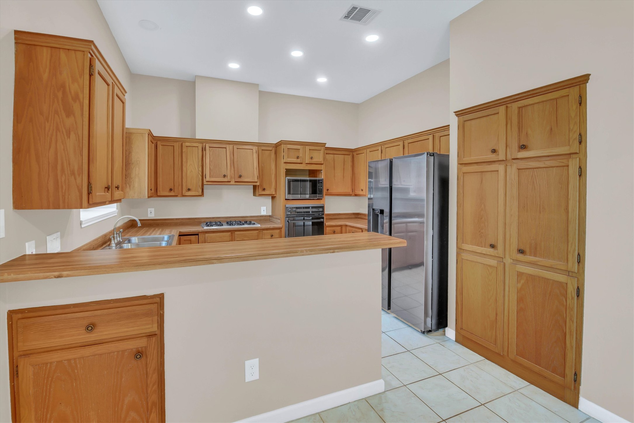 8108 Matchlock Cove Austin, TX 78729 - Photo 16 of 40 Kitchen with a peninsula, light countertops, stainless steel appliances, light tile patterned floors, and recessed lighting