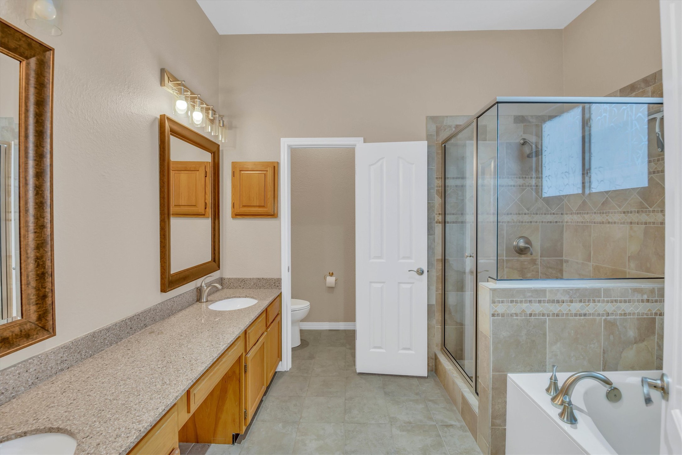 8108 Matchlock Cove Austin, TX 78729 - Photo 28 of 40 Full bath featuring double vanity, a shower stall, a bath, and light tile patterned flooring