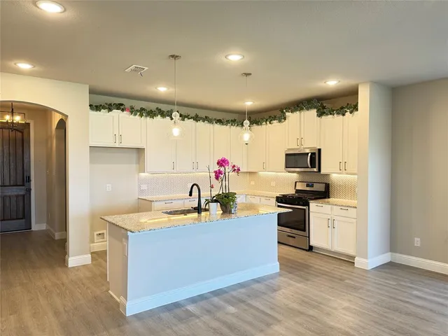 a kitchen with stainless steel appliances granite countertop a sink dishwasher stove top oven and refrigerator