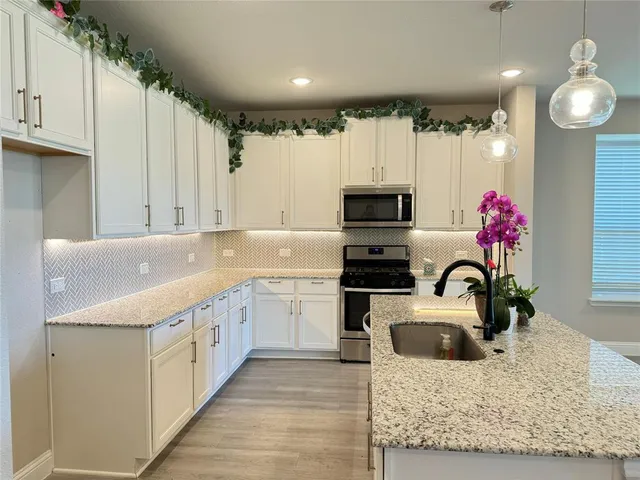 a kitchen with granite countertop a sink stainless steel appliances and cabinets