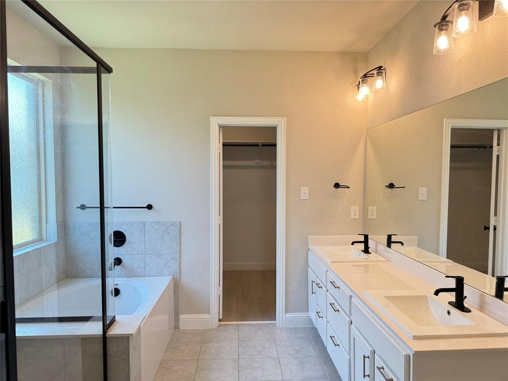 7308 Roaring Springs Road Arlington, TX 76002 - Photo 19 of 29 a bathroom with a double vanity sink a mirror and a bathtub