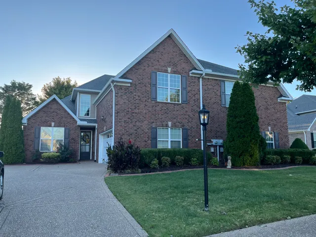 a front view of a house with a yard and green space