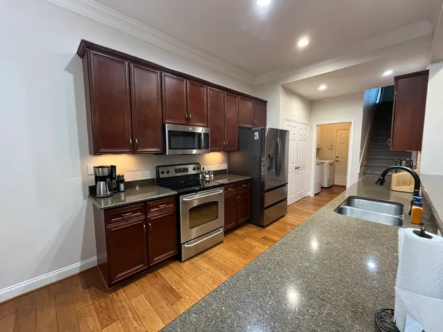 a kitchen with stainless steel appliances granite countertop a stove a sink dishwasher a refrigerator and a microwave oven with wooden floor