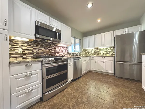 a kitchen with stainless steel appliances granite countertop a refrigerator stove a sink dishwasher and microwave