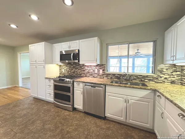 a kitchen with granite countertop white cabinets and stainless steel appliances