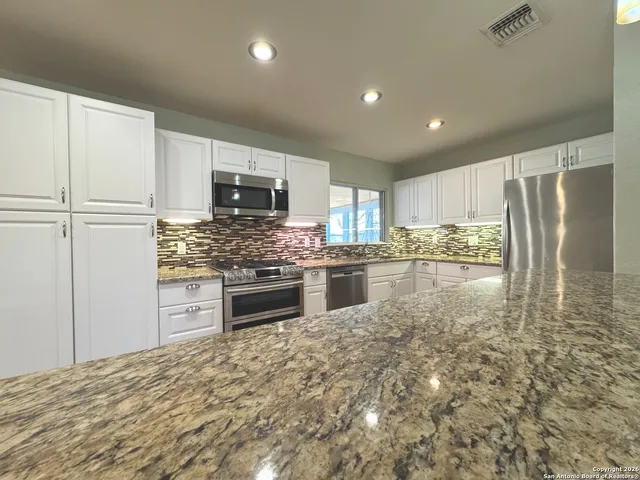 a kitchen with granite countertop a refrigerator and a stove top oven