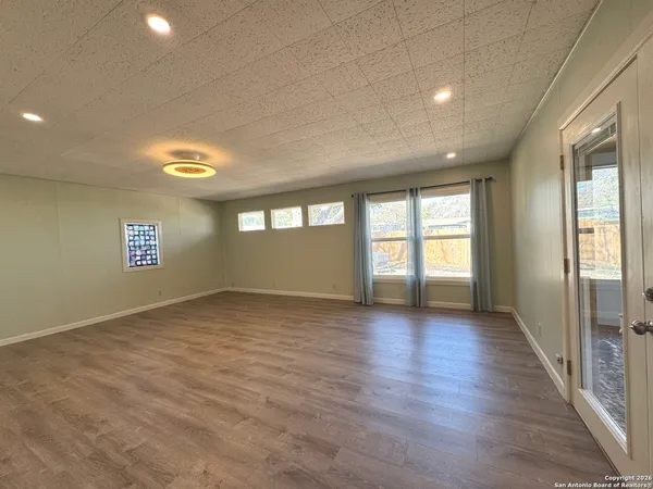 an empty room with wooden floor and windows