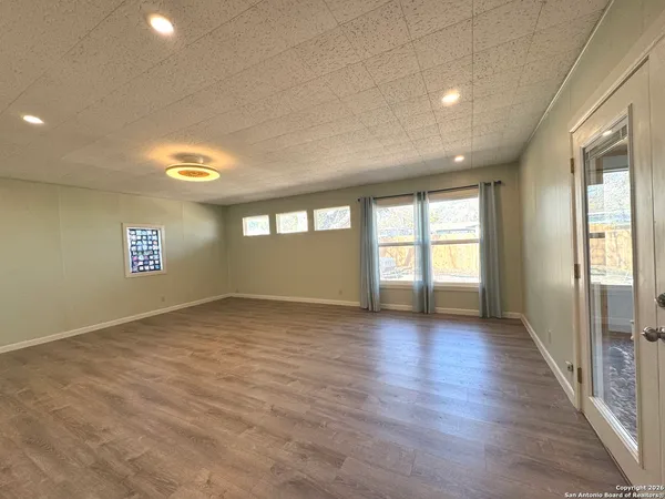 a view of kitchen and empty room with wooden floor