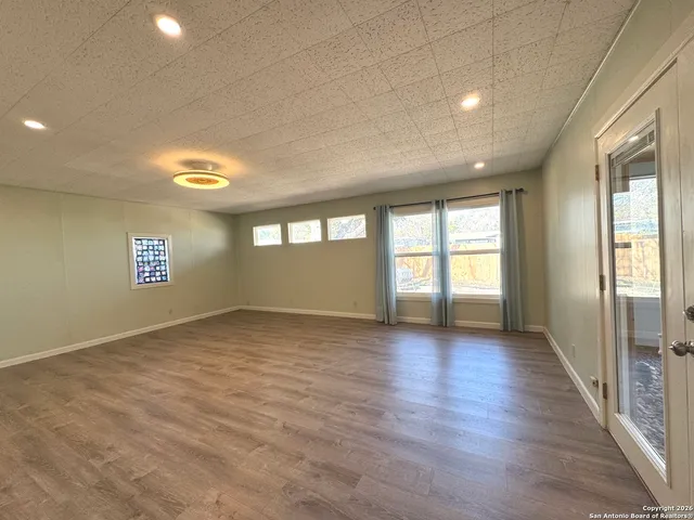 a view of kitchen and empty room with wooden floor