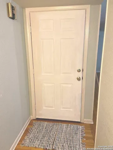 a view of a room with wooden floor and white door