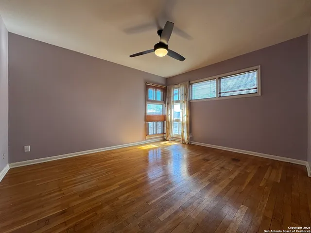 a view of an empty room with window and wooden floor