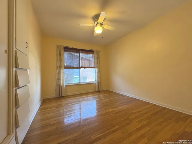 a view of an empty room with wooden floor and a window