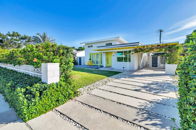 a front view of a house with a yard and potted plants