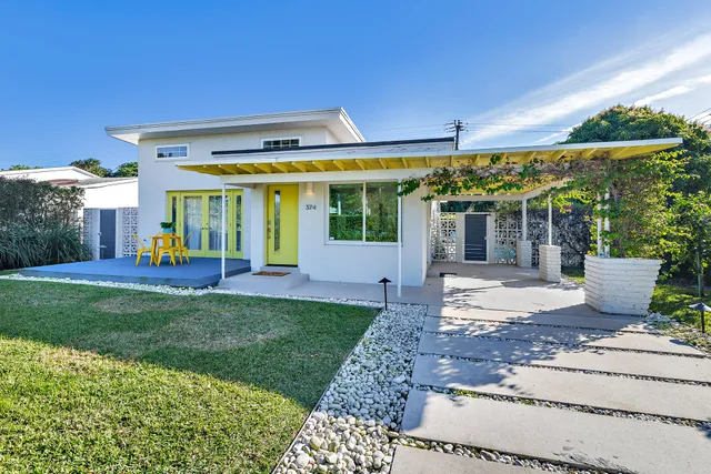a view of a house with a big yard and large tree