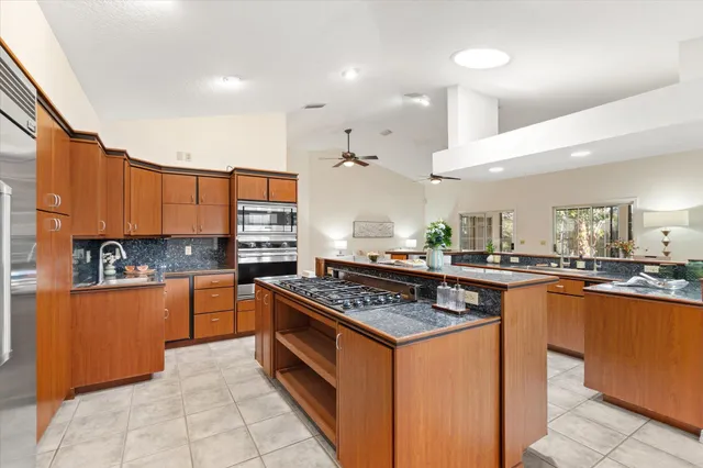 a kitchen with stainless steel appliances granite countertop a stove a sink dishwasher and a refrigerator with wooden cabinets