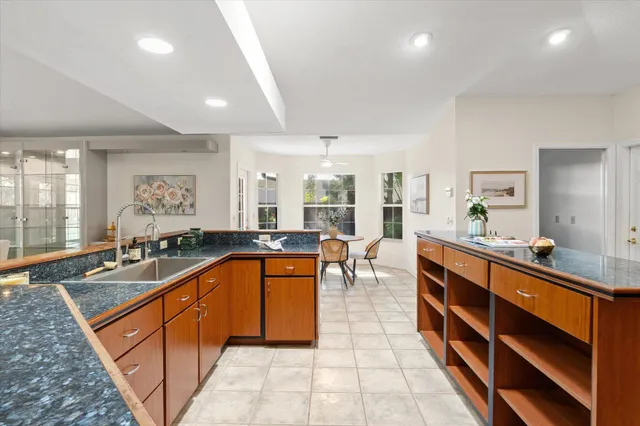 a large kitchen with stainless steel appliances a large counter top a sink and living room view