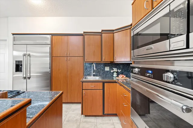 a kitchen with stainless steel appliances granite countertop a sink and a refrigerator