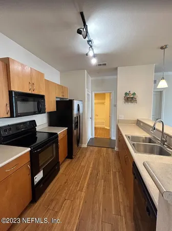 a kitchen with stainless steel appliances a sink dishwasher stove and oven with wooden floor