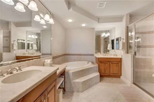 a bathroom with a tub double vanity sink and a mirror