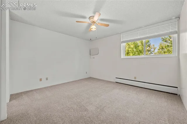 an empty room with a window and ceiling fan