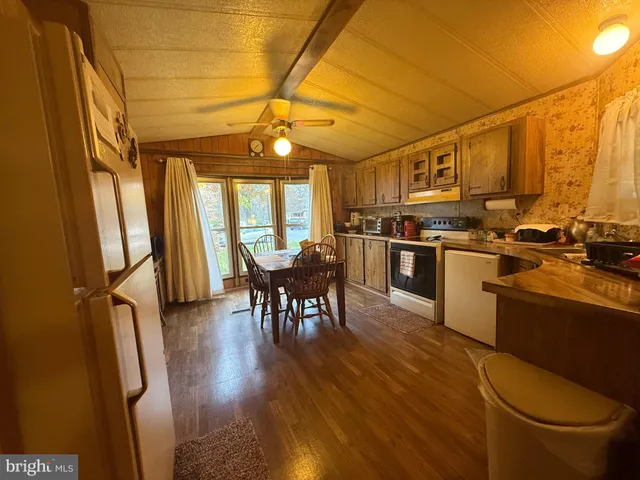 a kitchen with stainless steel appliances a stove a refrigerator a sink a dining table and chairs with wooden floor