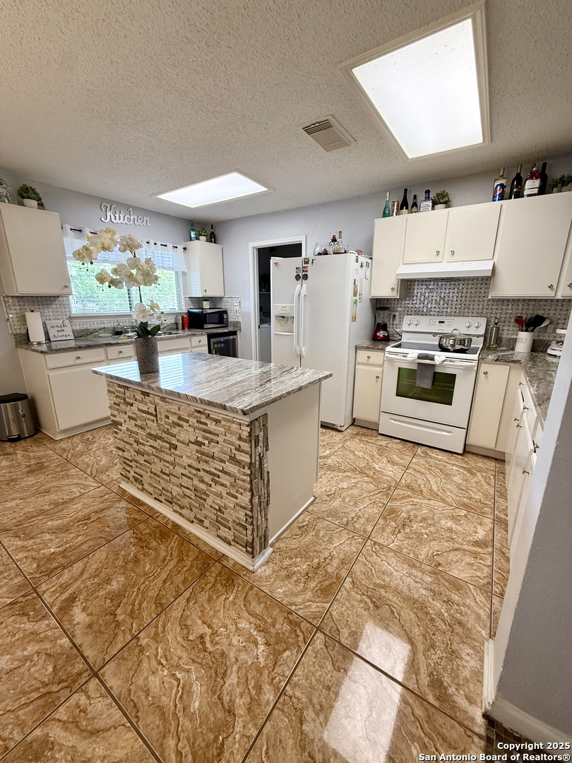 6719 Raintree Path San Antonio, TX 78233 - Photo 9 of 24 a kitchen with kitchen island granite countertop a stove and a sink