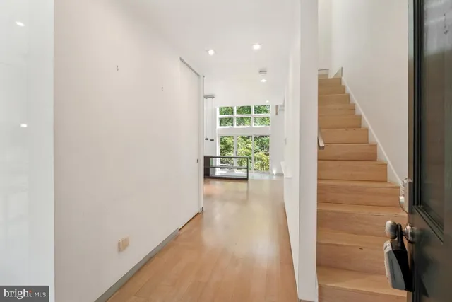 a view of a hallway to a livingroom with wooden floor and stairs