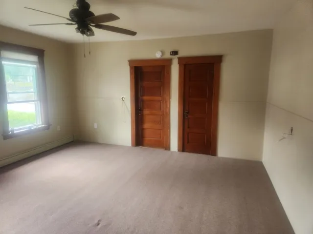 an empty room with windows and fan