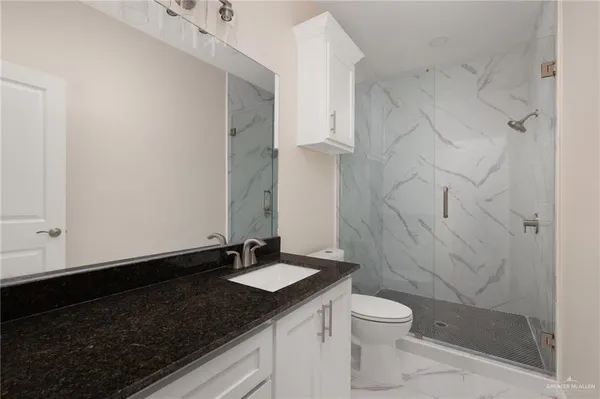 a bathroom with a granite countertop sink toilet a mirror and shower