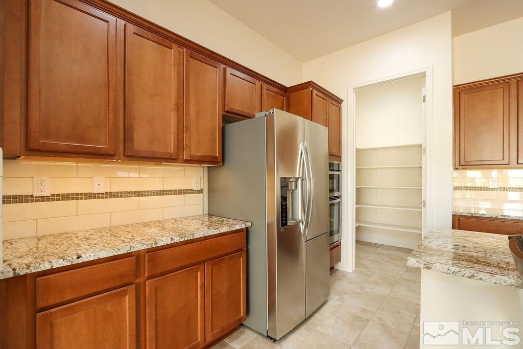 9410 Stony Hill Road Reno, NV 89521 - Photo 18 of 39 a kitchen with stainless steel appliances granite countertop a refrigerator and a stove top oven
