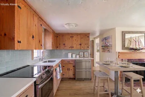 a kitchen with stainless steel appliances granite countertop a stove top oven a sink dishwasher and white cabinets with wooden floor