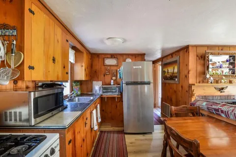 a kitchen with stainless steel appliances granite countertop a refrigerator a stove and a sink with wooden floor