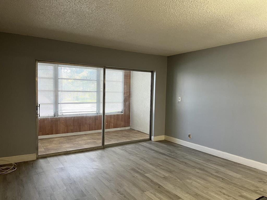 8810 West McNab Road, Unit 205 Tamarac, FL 33321 - Photo 2 of 11 an empty room with wooden floor and windows