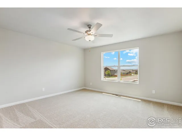 an empty room with windows and ceiling fan