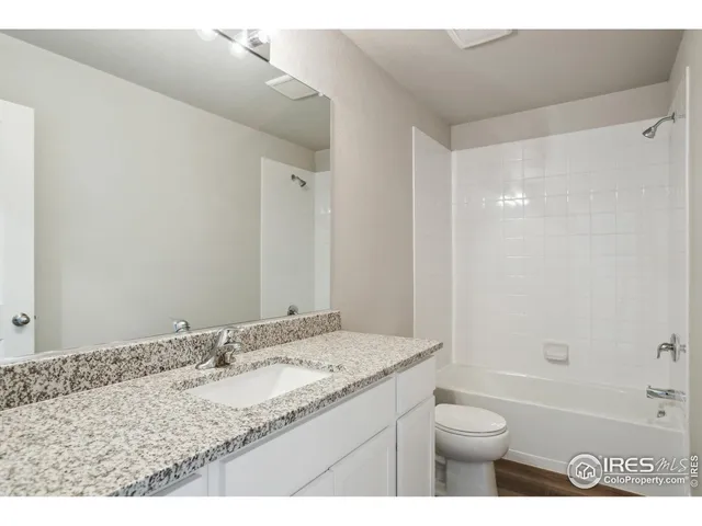a bathroom with a granite countertop sink a toilet and shower