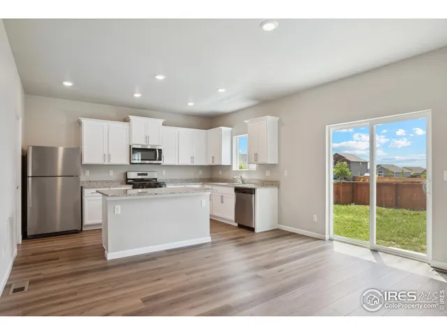 a kitchen with a refrigerator and wooden floor