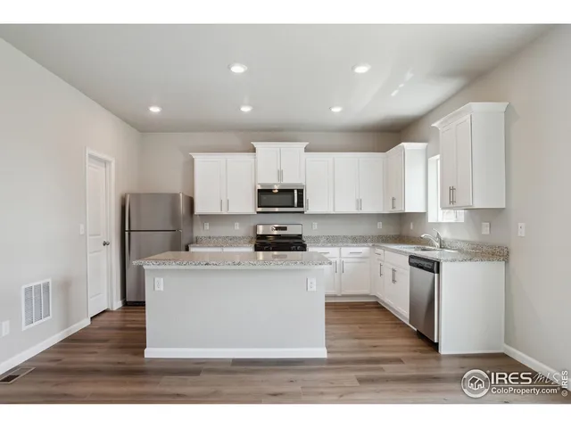 a kitchen with stainless steel appliances granite countertop a stove top oven a sink and a refrigerator
