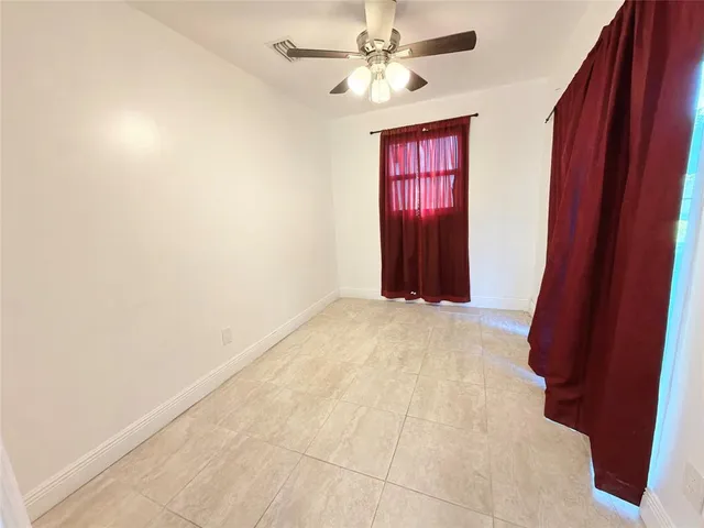 an empty room with windows and fan