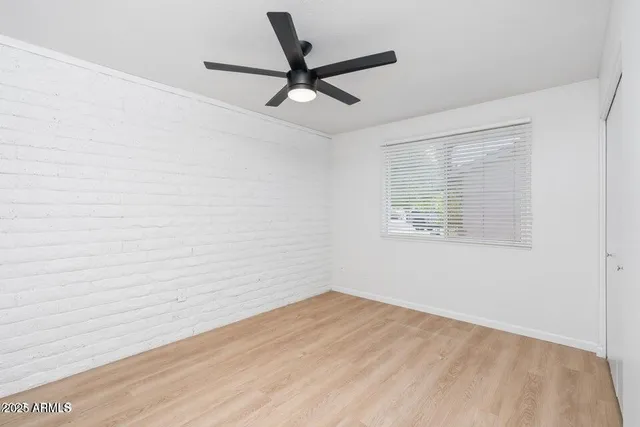 a view of empty room with wooden floor and ceiling fan