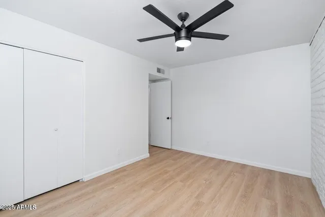 an empty room with a ceiling fan and wooden floor