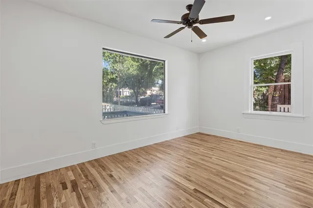a view of empty room with wooden floor and fan