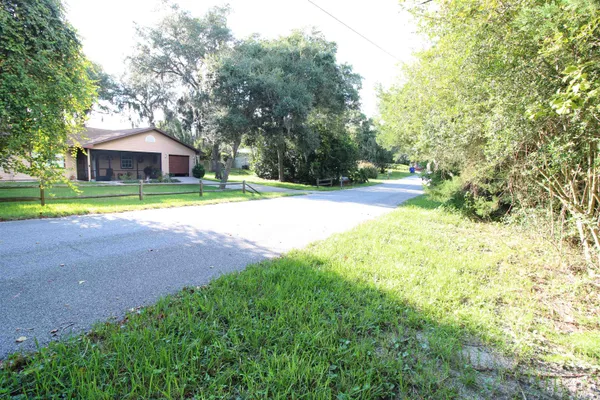 a view of a house with a yard and large trees