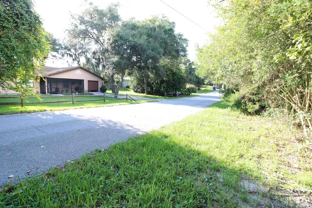 a view of a house with a yard and large trees